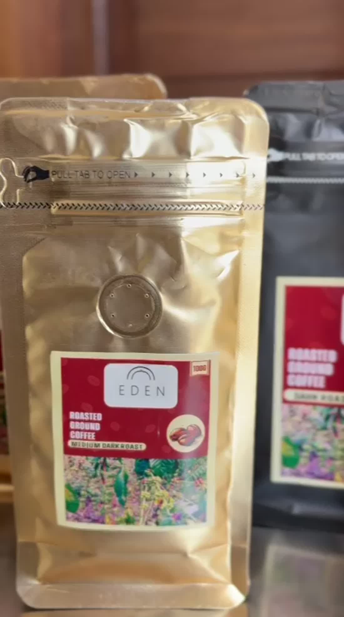 Eden Coffee medium dark roast in a gold pouch beside the dark roast in a black pouch